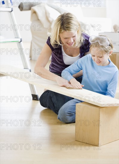 Mother and daughter sanding wood plank. Date : 2008