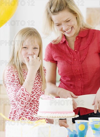 Mother and daughter next to birthday cake. Date : 2008