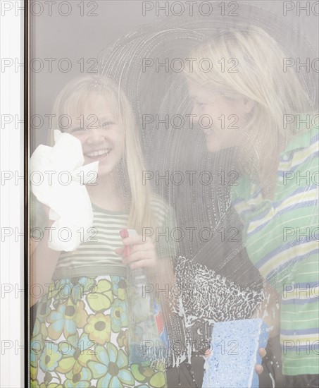 Mother and daughter washing window. Date : 2008