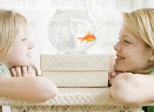 Mother and daughter looking at fish in bowl. Date : 2008