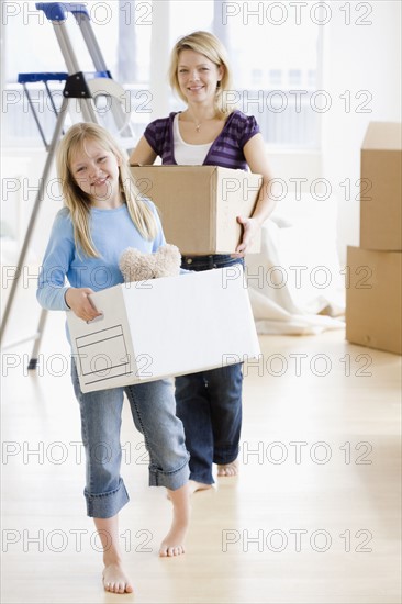 Mother and daughter carrying moving boxes. Date : 2008