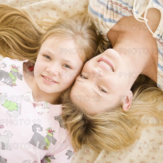 Mother and daughter laying on bed. Date : 2008