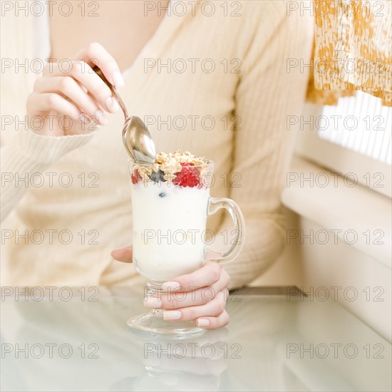 Woman eating breakfast parfait. Date : 2008