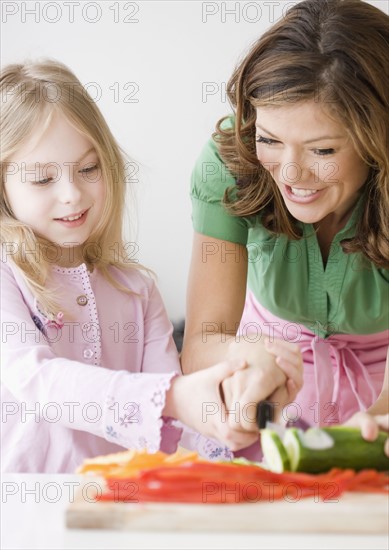 Mother helping daughter chop vegetables. Date : 2008