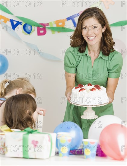 Mother holding birthday cake at party. Date : 2008