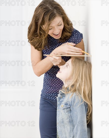 Mother measuring daughter’s height. Date : 2008