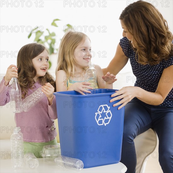 Mother and daughters filling recycling bin. Date : 2008