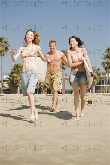 Friends carrying surfboards at beach. Date : 2008