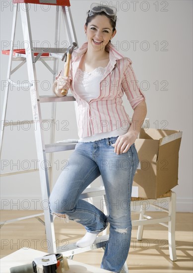 Woman holding hammer next to ladder. Date : 2008