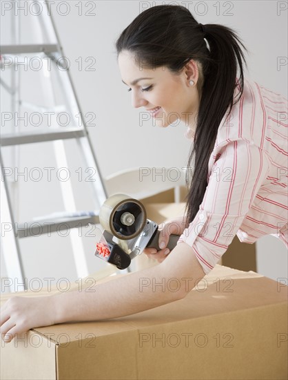 Woman sealing moving box with tape. Date : 2008