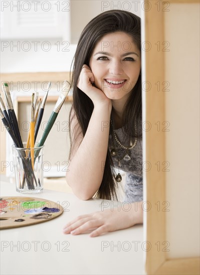 Woman next to paintbrushes and canvas. Date : 2008