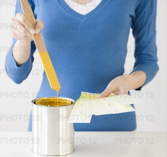 Woman holding paint swatches next to paint can. Date : 2008