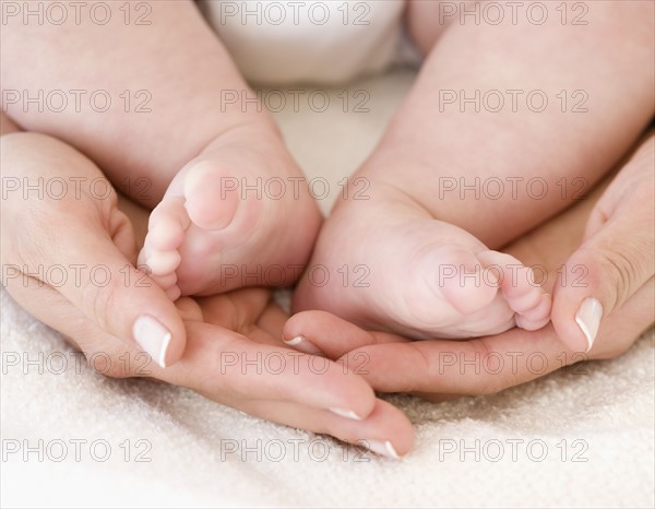 Close up of mother’s hands and baby’s feet. Date : 2008