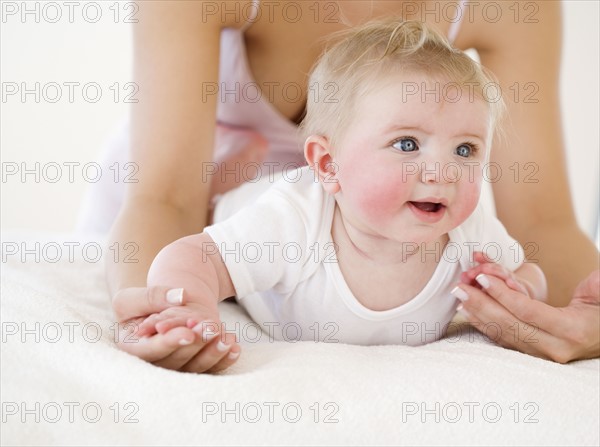 Mother leaning over baby on bed. Date : 2008