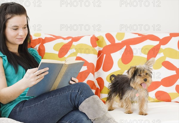 Woman reading on sofa next to dog. Date : 2008