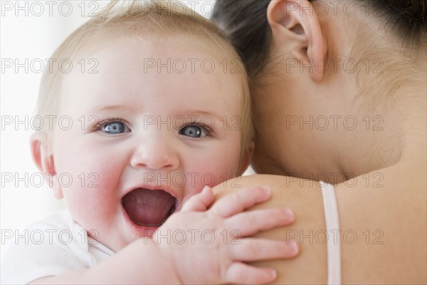 Baby laughing over mother’s shoulder. Date : 2008