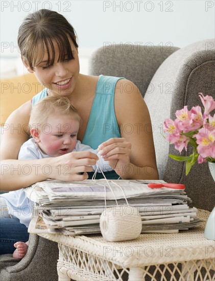 Mother and baby bundling newspapers. Date : 2008