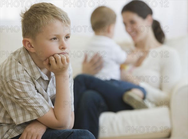 Boy thinking in front of mother and baby.