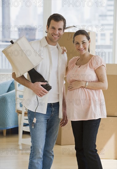 Pregnant Hispanic couple in new house.