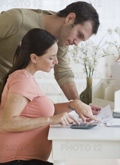 Pregnant Hispanic couple paying bills.