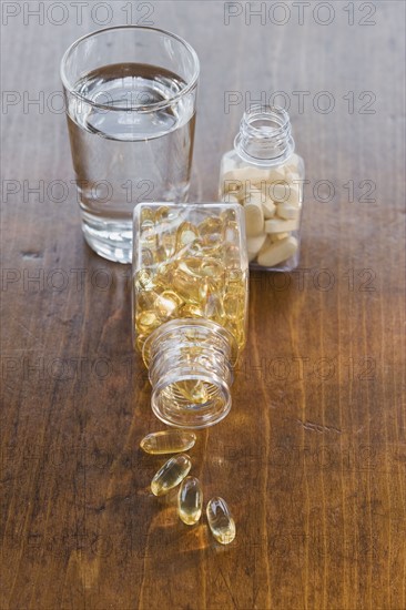 Vitamins in bottles next to water.