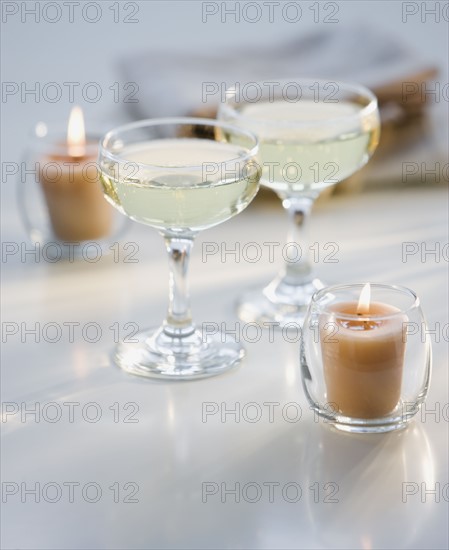 Glasses of champagne next to candles.