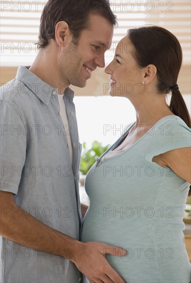 Pregnant Hispanic couple hugging.