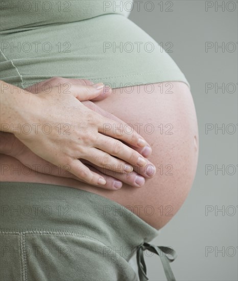 Couple’s hands on pregnant belly.