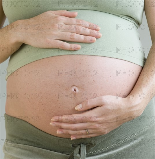 Pregnant woman with hands on belly.