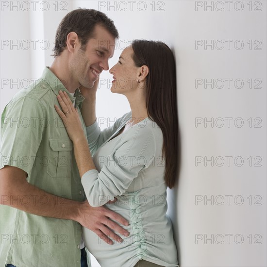 Pregnant Hispanic couple hugging.