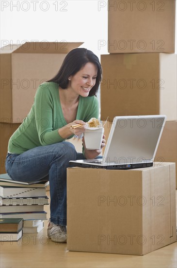 Woman eating take out food in new house.