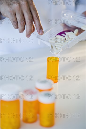Pharmacist filling pill bottle.