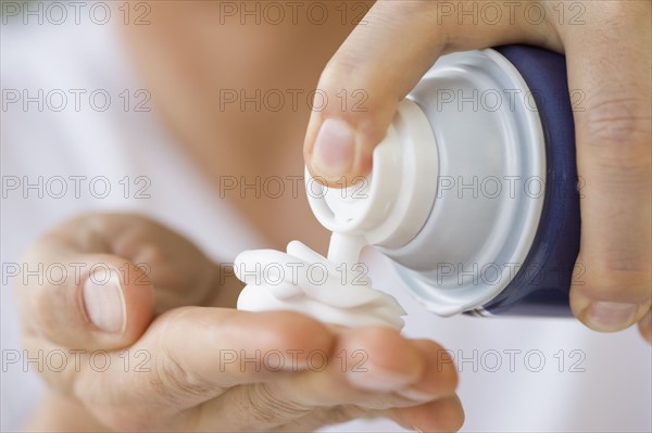 Man dispensing shaving cream into hand.