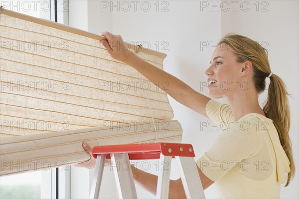 Woman hanging window blinds.