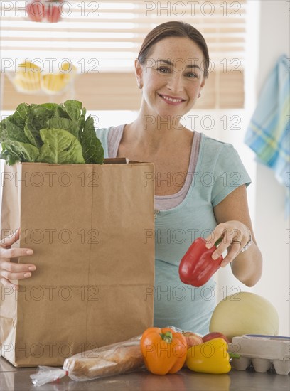 Pregnant Hispanic woman unpacking groceries.