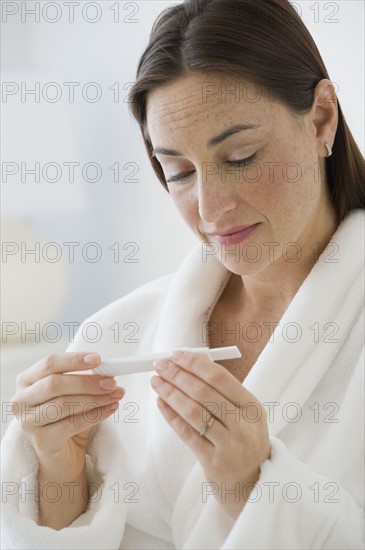 Hispanic woman looking at pregnancy test.