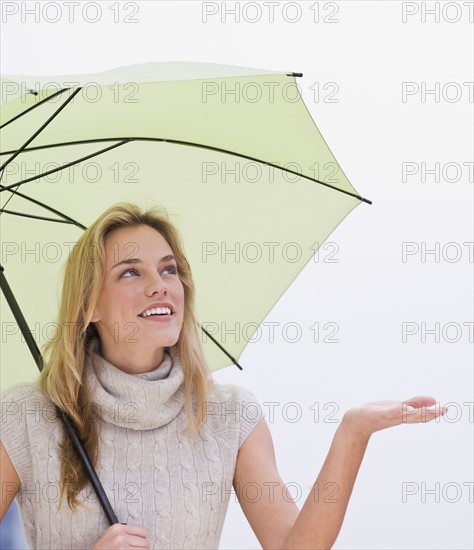 Woman holding hand out from under umbrella.