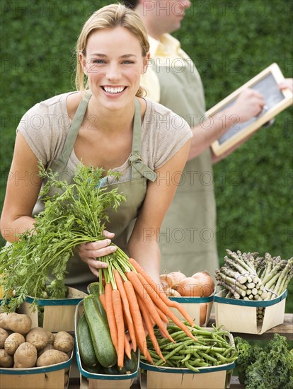 Woman next to baskets of vegetables.