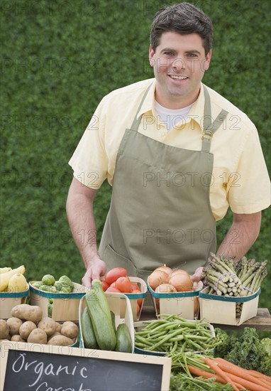 Man next to baskets of vegetables.