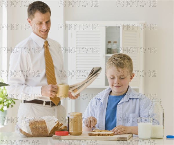 Father watching son make sandwich.