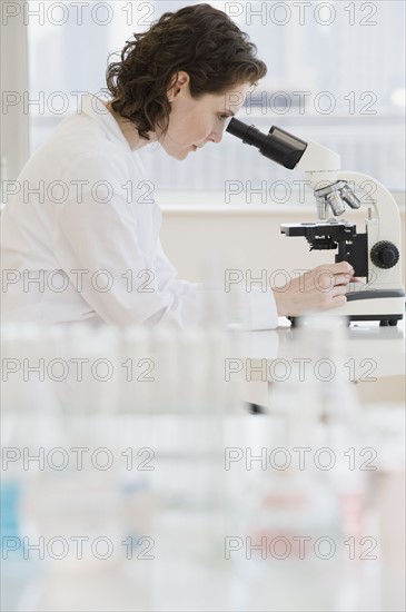 Female scientist looking into microscope.