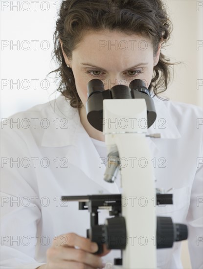 Female scientist looking into microscope.