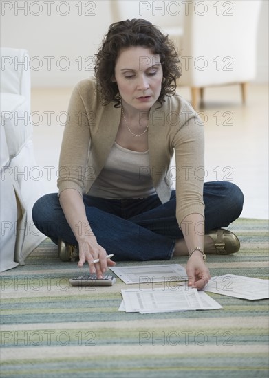 Woman paying bills on floor.