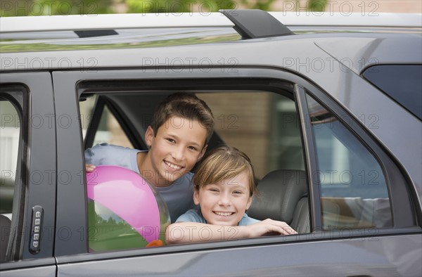 Brother and sister looking out car window.