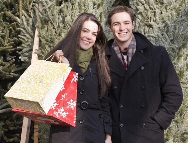 Couple with shopping bags in front of Christmas trees. Date : 2008