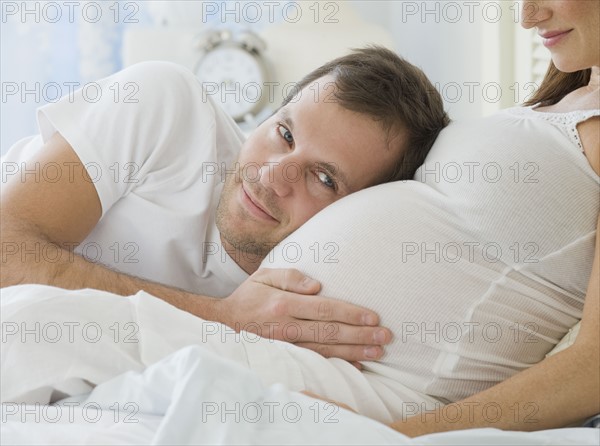 Hispanic man resting head on pregnant wife.