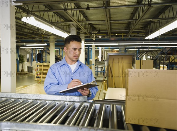 Asian male factory worker checking product. Date : 2008