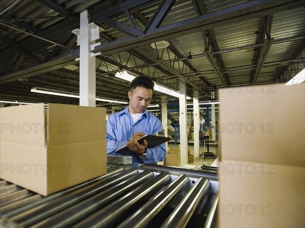 Asian male factory worker checking product. Date : 2008