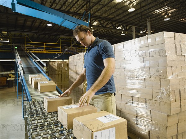 Warehouse worker checking packages on conveyor belt. Date : 2008