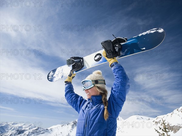 Woman holding snowboard over head. Date : 2008